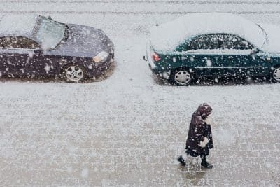 Photographie d’une rue enneigée avec des voitures sous la neige pour illustrer l’article d’Adesa sur l’entretien des pare-brises en hiver.