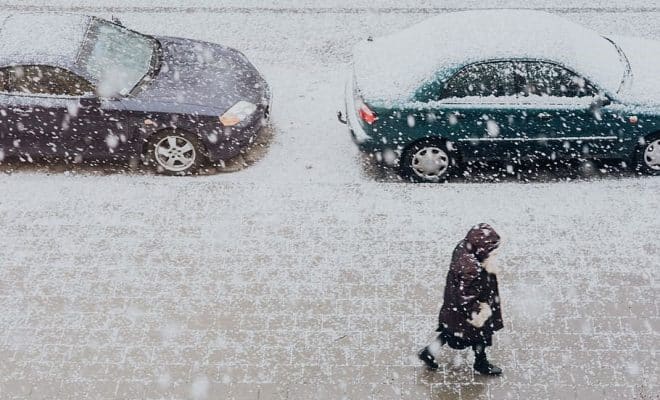 Photographie d’une rue enneigée avec des voitures sous la neige pour illustrer l’article d’Adesa sur l’entretien des pare-brises en hiver.