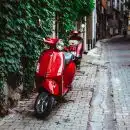 red motor scooter parked beside green plants