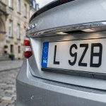 Plaque d'immatriculation luxembourgeoise avec la lettre L et le symbole européen sur un véhicule garé dans une rue pavée de Luxembourg-Ville