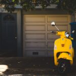 yellow motor scooter parked near white garage door