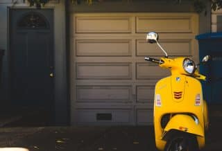 yellow motor scooter parked near white garage door