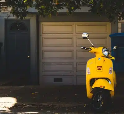 yellow motor scooter parked near white garage door