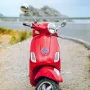 red Vespa motor scooter on side of the road