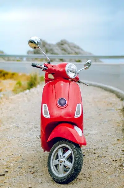 red Vespa motor scooter on side of the road