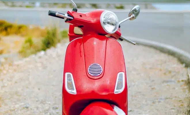 red Vespa motor scooter on side of the road